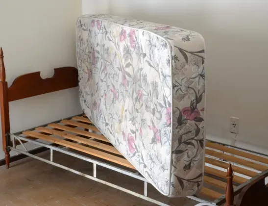 old mattress standing on its side on a bed frame